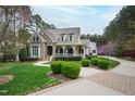 Beautiful home featuring a brick driveway, lush landscaping, and a charming stone and shingle facade at 125 Dartmoor Ln, Raleigh, NC 27614