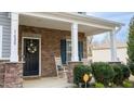 Cozy covered front porch with rocking chairs, stone accents, and a decorative front door wreath at 1620 Frog Hollow Way, Wake Forest, NC 27587