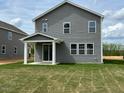 Backyard featuring new construction home, showing green grass, and sliding door on a sunny day at 183 Little Crk Dr, Lillington, NC 27546