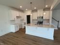 Modern, bright kitchen featuring white cabinets, stainless steel appliances, large island with pendant lighting at 183 Little Crk Dr, Lillington, NC 27546