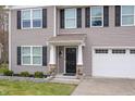 Close-up of the home's inviting front entry with a black front door and stone accents at 211 Richmond Run, Stem, NC 27581