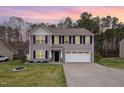 Charming two-story home featuring a well-maintained lawn and a two-car garage at dusk at 211 Richmond Run, Stem, NC 27581