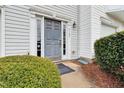 Stylish gray front door with sidelights and a welcome mat, surrounded by green bushes at 5163 Sandy Banks Rd, Raleigh, NC 27616