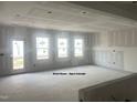 Unfinished great room featuring drywall, large windows, and open-concept layout at 6002 Shade Tree Ln, Durham, NC 27703