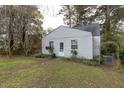 Charming single-story home featuring light siding, windows and a mailbox surrounded by lush greenery and trees at 1203 Brookside Dr, Raleigh, NC 27604