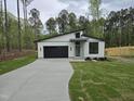 Modern home exterior featuring a black garage door, contemporary design, and a spacious driveway at 124 Horseman Dr, Louisburg, NC 27549