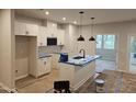 Bright, modern kitchen featuring an island with a sink and white cabinets with black hardware at 1352 Bessie Ct, Wake Forest, NC 27587