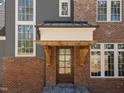 Close-up of the front door showcasing a wooden door with a decorative wooden portico and brick facade at 1425 Lake Adventure Ct, Raleigh, NC 27613