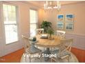 Staged dining room featuring a round table, chandelier, and natural light from the surrounding windows at 1623 Rogers Pointe Ln, Creedmoor, NC 27522
