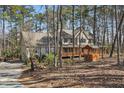 Two-story home with a full front porch nestled in mature trees, long drive way leading to the garage at 167 Coachmans Cove Rd, Four Oaks, NC 27524
