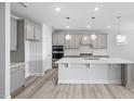 A modern kitchen is equipped with stainless steel appliances, an island, and gray cabinetry at 1805 Angelonia Way, Fuquay Varina, NC 27526