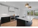 Modern kitchen with white cabinets, black island, stainless steel appliances and stylish pendant lighting at 1886 Mays Crossroad Rd, Louisburg, NC 27549
