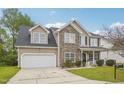 Charming two-story home featuring a stone facade, a two-car garage, and a well-maintained front yard at 2223 Lazy River Dr, Raleigh, NC 27610