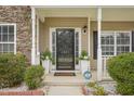 Welcoming front porch with decorative plants, a security system sign, and a stylish front door at 2223 Lazy River Dr, Raleigh, NC 27610