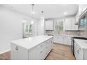 Spacious kitchen with white cabinets, stainless appliances, a center island, and hardwood floors at 2316 Beeblossom Pl, Fuquay Varina, NC 27526
