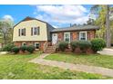 Traditional two-story home featuring a brick facade and vinyl siding, complimented by a well-maintained lawn and landscaping at 5401 Kaplan Dr, Raleigh, NC 27606