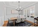 Elegant dining room with hardwood floors, large windows, modern chandelier, and stylish furniture for entertaining at 609 Meyers Place Ln, Holly Springs, NC 27540
