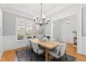 Elegant dining room with hardwood floors, large windows, modern chandelier, and stylish furniture for entertaining at 609 Meyers Place Ln, Holly Springs, NC 27540