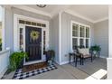 Inviting front porch featuring a charming door with wreath, comfortable seating, and stylish decorations and potted greenery at 609 Meyers Place Ln, Holly Springs, NC 27540