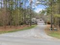 Exterior view of the property with a long gravel driveway, well-kept lawn, and surrounded by lush trees at 707 Sinai Cir, Hillsborough, NC 27278