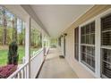 Inviting front porch featuring white columns, views of the front yard, and exterior window shutters at 707 Sinai Cir, Hillsborough, NC 27278