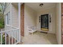 Inviting front porch with neutral siding, brick accents, and a cozy bench at 8325 Wycombe Ln, Raleigh, NC 27615