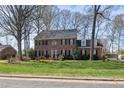 Charming brick home featuring classic architectural details, a lush green lawn, and mature shade trees at 1005 Brookview Dr, Elon, NC 27244