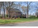 Traditional brick home with a well-kept lawn, showcasing mature trees and classic design elements at 1005 Brookview Dr, Elon, NC 27244