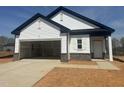 New construction home showcasing white siding, brick accents, and an attached two-car garage with an open door at 11778 Salers Loop, Middlesex, NC 27557