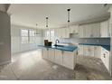 White kitchen with an island, pendant lights, and stainless steel appliances with large windows at 141 Ruskin Dr, Smithfield, NC 27577