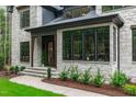 Elegant home entrance with stone facade, dark trim windows and manicured landscaping at 2200 Paddstowe Main Way, Wake Forest, NC 27587