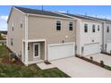 Rear view of modern townhome featuring an attached garage, back door, and manicured lawn at 2313 Kasota Ln, Raleigh, NC 27610