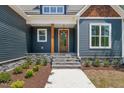 Inviting front porch with stone steps, wooden pillars, and a stylish wooden door at 390 Pilot Ridge Rd, Zebulon, NC 27597
