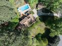 Aerial view of a home with a pool, deck, and lush green landscaping with a long driveway at 6216 Woodmark Trl, Raleigh, NC 27606