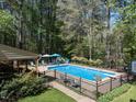 Fenced backyard pool area features chairs, patio and ample lounging space amid lush greenery at 6216 Woodmark Trl, Raleigh, NC 27606