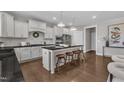 Stylish kitchen with an island, white cabinetry, modern appliances, and hardwood floors; great for entertaining guests at 706 Fireball Ct, Knightdale, NC 27545