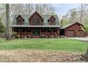 Charming log home with a covered front porch and dormer windows adjacent to matching two-car garage at 932 Gynnis Creek Dr, Moncure, NC 27559