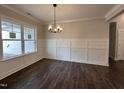 Bright dining room featuring an elegant chandelier, decorative wainscotting, and hardwood floors at 104 Roma Gora Ct, Princeton, NC 27569