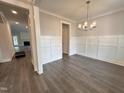 Bright dining room showcasing wainscoting, hard wood floors, and modern chandelier at 106 Roma Gora Ct, Princeton, NC 27569