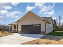 The garage of a light yellow house has a dark brown garage door and a well maintained concrete driveway at 122 Wilderness Trl, Smithfield, NC 27577