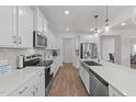 Open kitchen design with white cabinets, quartz counters, stainless appliances and hardwood floors at 125 Paperwhite Pl, Clayton, NC 27527