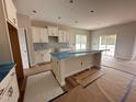 Well-lit kitchen featuring an island, sleek countertops, and ample cabinet space at 125 Tuskeegee Dr, Smithfield, NC 27577