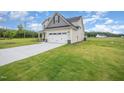 View of the tan house with green grass and large driveway leading to the garage at 21 Trescott St, Smithfield, NC 27577