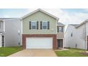 Two-story home featuring a white garage door, brick facade, green siding, and a well-manicured lawn at 2153 Monk Dr, Haw River, NC 27258