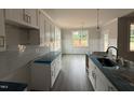 Well-lit kitchen with white cabinetry, modern countertops, and a spacious layout, adjacent to a dining nook at 221 Tee Dr, Selma, NC 27576