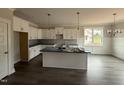 Elegant kitchen featuring white cabinets, an island with sink, and modern pendant lighting, open to the dining area at 221 Tee Dr, Selma, NC 27576