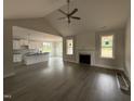 Bright living room featuring high ceilings, fireplace, and hardwood floors, seamlessly transitioning into the open kitchen space at 221 Tee Dr, Selma, NC 27576