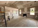 Unfinished living room featuring fireplace, vaulted ceiling, and abundant natural light from multiple windows at 221 Tee Dr, Selma, NC 27576