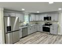 Well-lit kitchen featuring gray cabinets, stainless steel appliances, granite counters, and hardwood floors at 2316 Radiance Dr, Burlington, NC 27215