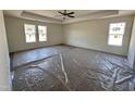 Large bedroom with tray ceiling, ceiling fan and bright natural light from many windows at 253 Trescott St, Smithfield, NC 27577